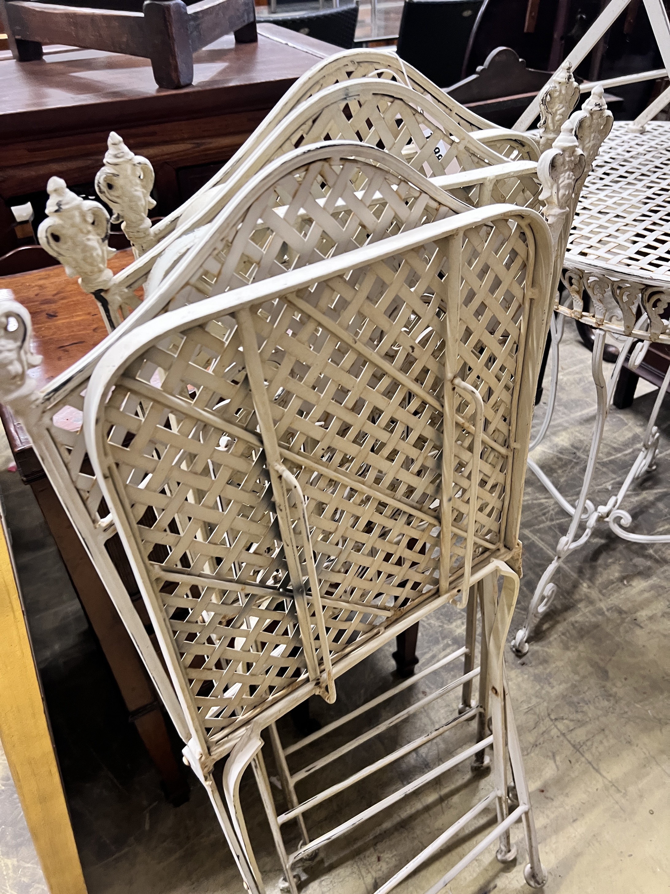 A white painted wrought iron garden table and four folding chairs